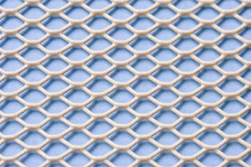 White metal mesh with small cells on a blue background. Close-up. Macro. Industrial background