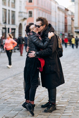 Young handsome curly man in sunglasses kiss his attractive girlfriend on the city street