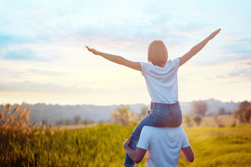 Portrait of young man holding on shoulders his happy girlfriend, she spread apart arms mimicking...