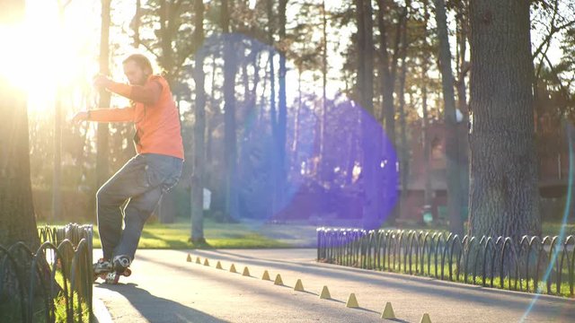 Cool roller trains his roller skating technique, rides backwards and crosses legs and drives between cones. Down view training of an experienced bearded athlete in fine sunny weather in slow motion.