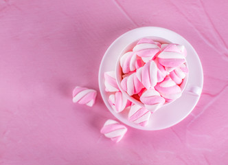 Pink marshmallows background in a white cup, dessert pastel tones, sweet dishes. Background or texture of colorful mini marshmallows