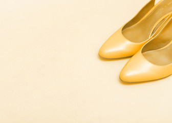 A pair of yellow women's shoes on light yellow background. Flat lay, copy space.