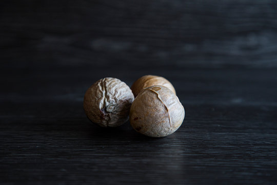 Low key image of 3 different sized avocado seeds in a group. Hard light shows the veins and dry skin layer of the pips. A lot of detail can be seen. Natural portrait, dark background, brown, black