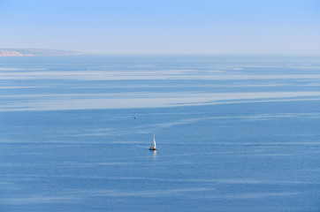 Naklejka premium Volga river near Ulyanovsk, Russia. Blue background of sky and water with a sail in the distance
