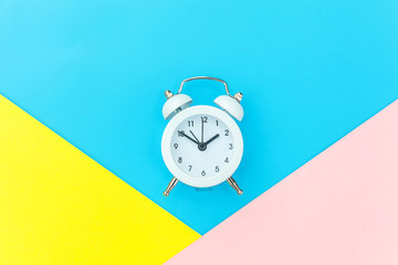 Ringing twin bell classic alarm clock isolated on blue yellow pink pastel colorful geometric background. Rest hours time of life good morning night wake up awake concept. Flat lay top view copy space