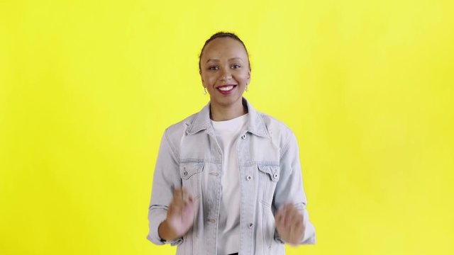 Beautiful happy african young woman surprised while looking at the camera and saying OH MY GOD on yellow background Jean jacket