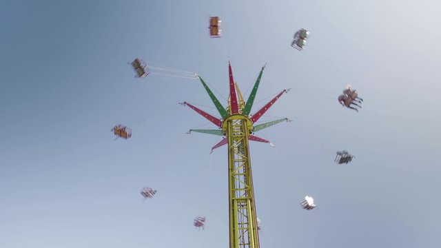 Sky swing swinging at funfair on a sunny day, looking from underneath