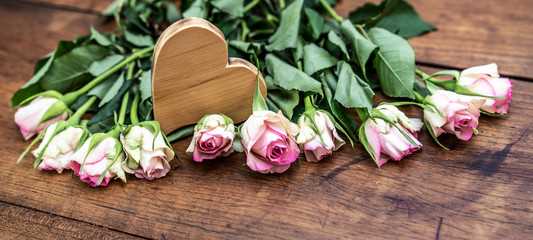 Pink roses and wooden heart on rustic wooden table - Flower background vintage