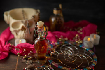 Fototapeta na wymiar Scary still life with potions, skull, mortar, vintage bottles and candles on witch table. Halloween or esoteric concept.