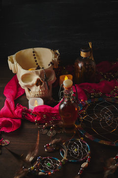 Scary still life with potions, skull, mortar, vintage bottles and candles on witch table. Halloween or esoteric concept.