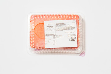 Black plastic pack with fresh hash isolated on white background. Raw meat packed with label top view, Symbol for environmental pollution done by the food industry