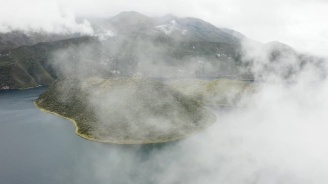 Aerial flies backwards covering the view with Fog. Cuicocha Islands. Otavalo, Ecuador.