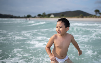 Boy playing  on sandy beach.  Happy kid on vacations at seaside on summer holidays. Children in nature with sea, sand and blue sky.