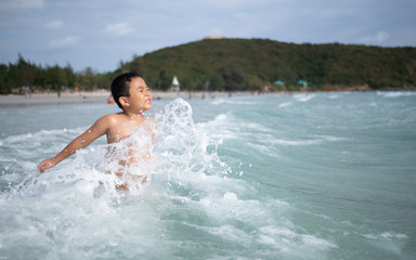 Fototapeta premium Boy playing on sandy beach. Happy kid on vacations at seaside on summer holidays. Children in nature with sea, sand and blue sky.