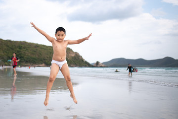 Boy playing  on sandy beach.  Happy kid on vacations at seaside on summer holidays. Children in...