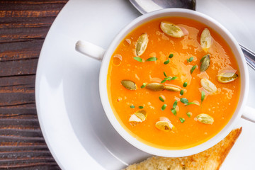 pumpkin cream soup on rustic wooden background