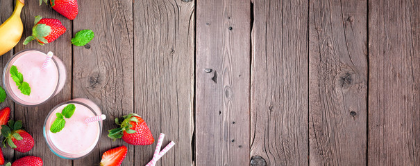 Obraz na płótnie Canvas Banner with healthy strawberry banana smoothie corner border. Above view over a rustic wood background. Copy space.