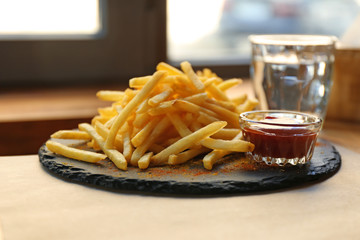 Tasty French fries with red sauce served on table in cafe