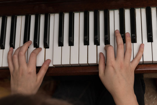 Hands of a girl playing the piano close-up