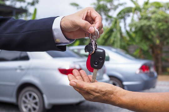 The car salesman sent the keys to the new car owner. Buying and selling rental concept