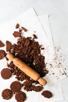 A wooden rolling pin crushing chocolate cookies in preparation for a recipe.