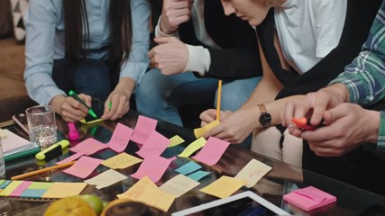 Closeup to the camera in a modern office center table big office team group analyzing the statistic plan of work make some notes on the small color paper