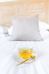 Herbal tea on bed linen in the upscale hotel room. Being alone, getaway, staycation, digital detox concepts. Vertical