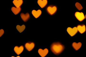 Black background with bright warm heart shaped bokeh lights. Holiday, Valentines Day background. Ideal to layer with any design. Horizontal