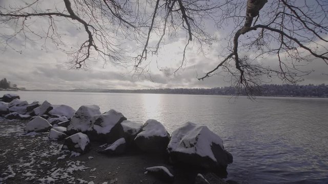 Washington State National Park, slow motion, tree branches and snowy ground framing a beautiful lake.