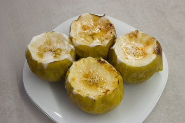 dessert dish: baked four apples with syrup on a white plate close-up