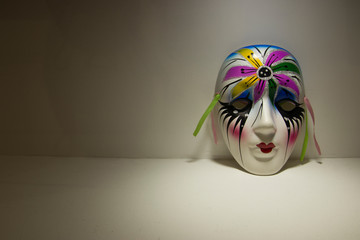 white ceramic mask painted with colorful paints close-up artistic light