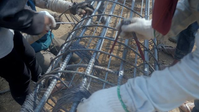 close up of workers making prefabricated  steel reinforcement cage for pile construction on site 