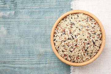 Mix of different brown rice on light blue wooden table, flat lay. Space for text