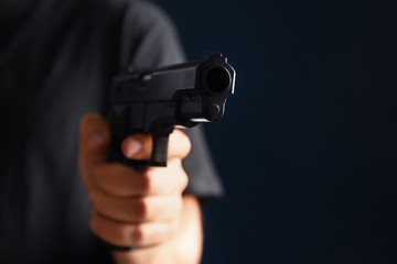 Man holding gun on dark background, closeup