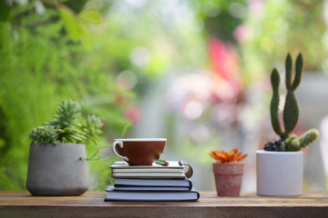 Brown coffee cup with notebooks and plants at outdoor