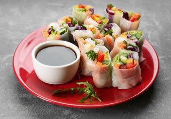 Delicious rolls wrapped in rice paper served on grey table