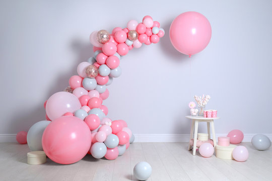 Beautiful composition with balloons and sweets near light wall
