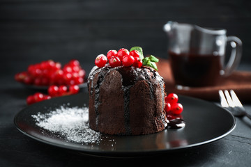 Delicious warm chocolate lava cake with mint and berries on dark grey table