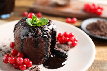 Delicious warm chocolate lava cake with mint and berries on plate, closeup