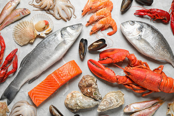 Fresh fish and seafood on marble table, flat lay