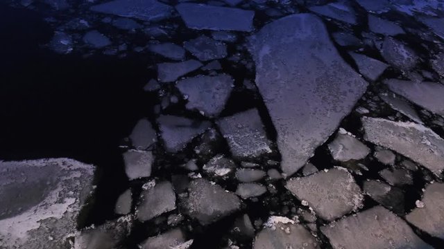 Small cracked pieces of ice on the water surface at the evening. Concept. Close-up view