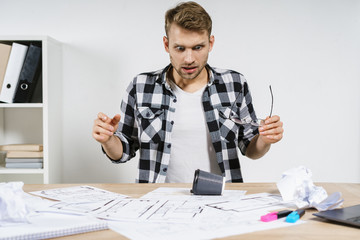 Young adult project manager and architect working in professional bureau with blueprints