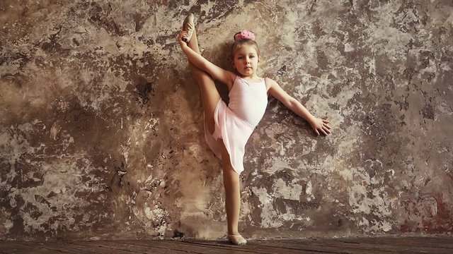 Child gymnast picks up a foot in the splits. Children's sports. flexibility and stretching. Slow motion