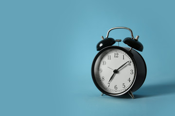 Alarm clock on light blue background, space for text. Morning time