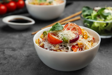 Tasty cooked rice noodles with vegetables on grey table