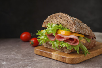 Tasty sandwich with ham on grey table against black background. Space for text
