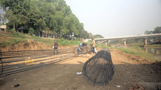 group of workers making prefabricated  steel reinforcement cage for pile construction on site