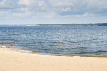 Fototapeta na wymiar sandy city beach with small waves and buoys