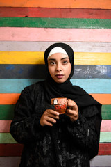 middle eastern girl in Arabic Traditional Abaya holding pottery tea cup
