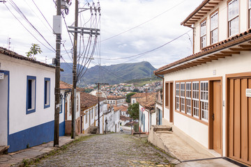 Steep descending cobble street of mining and colonial city in Minas with typical facades on either side